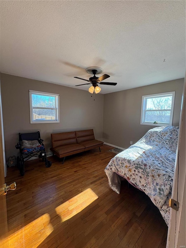 bedroom with a textured ceiling, multiple windows, a ceiling fan, and hardwood / wood-style floors