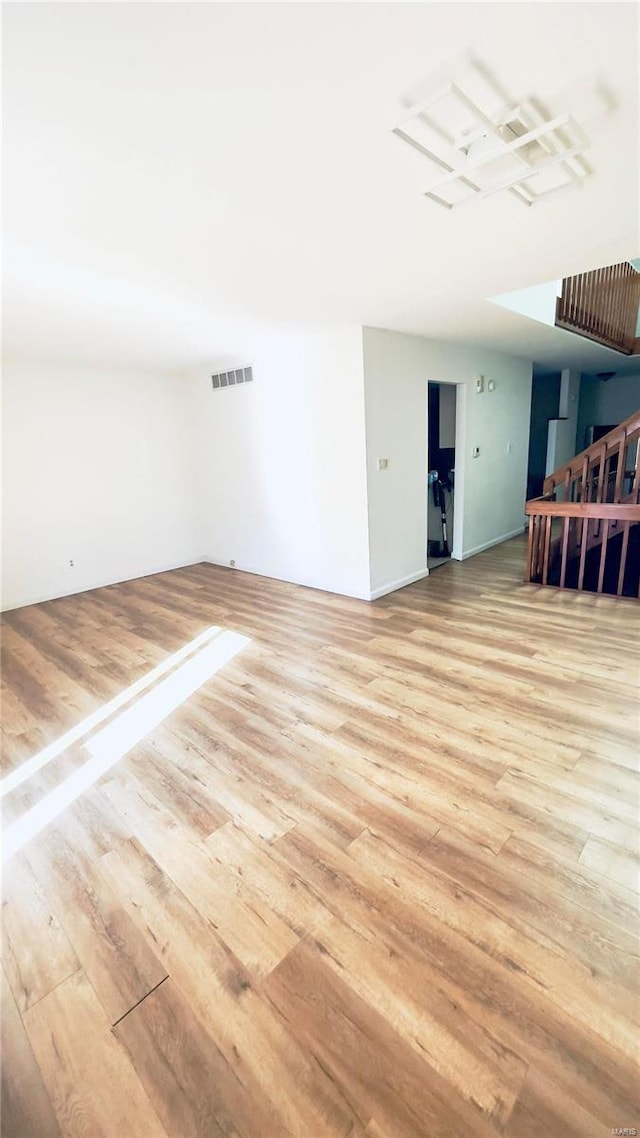 spare room featuring stairs, visible vents, and wood finished floors