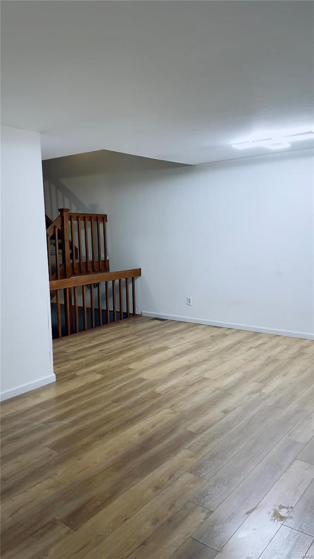 spare room featuring stairway, wood finished floors, and baseboards