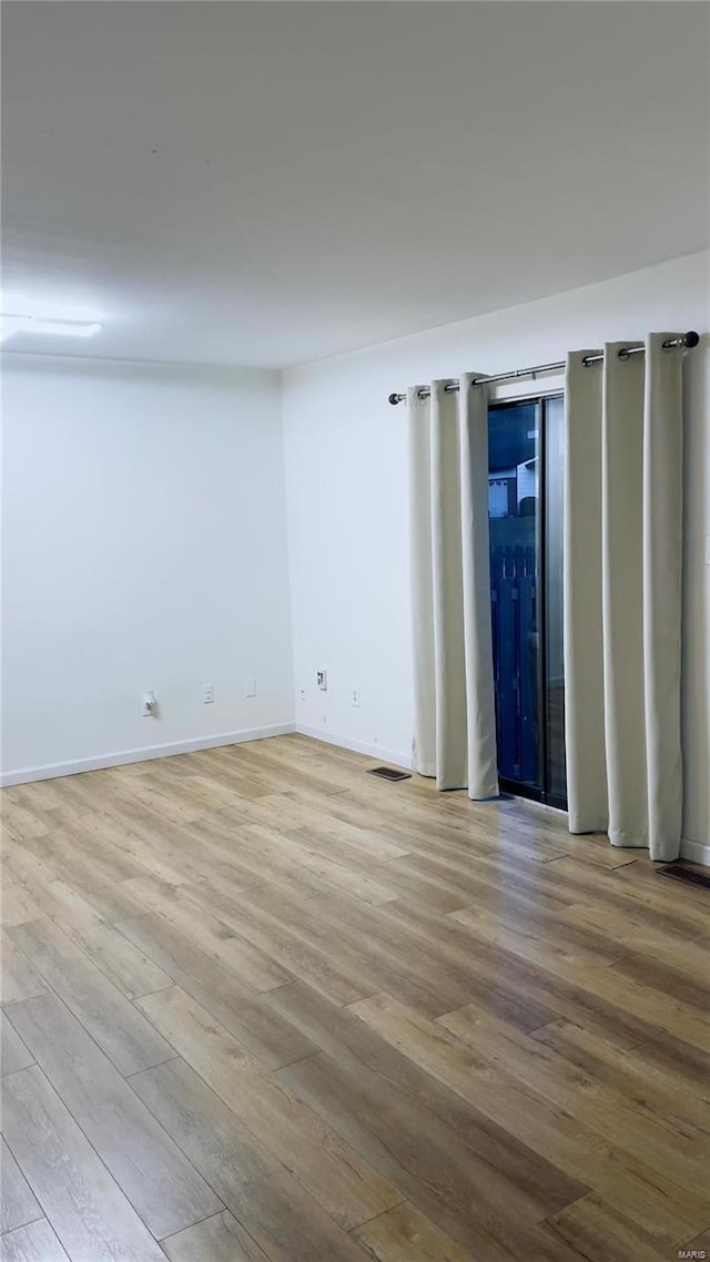 unfurnished room featuring baseboards, visible vents, and wood finished floors