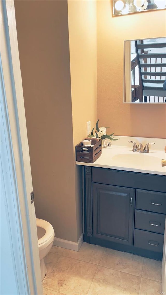 half bath featuring toilet, tile patterned flooring, vanity, and baseboards