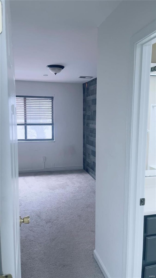 carpeted spare room featuring visible vents and baseboards