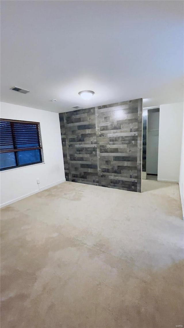 spare room featuring an accent wall, light colored carpet, visible vents, and baseboards