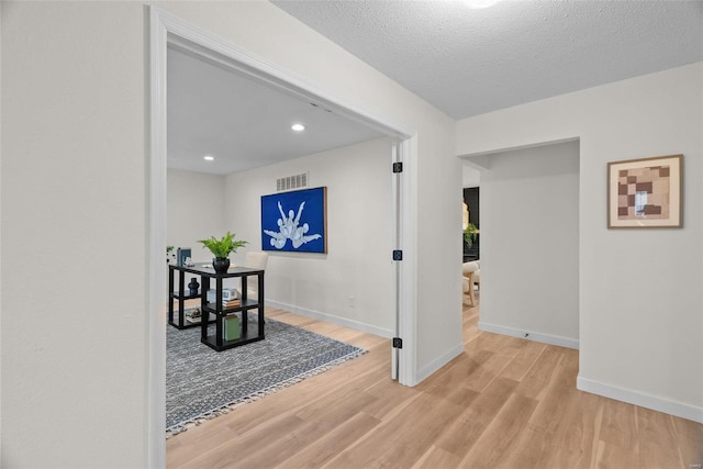 hall with baseboards, visible vents, wood finished floors, a textured ceiling, and recessed lighting