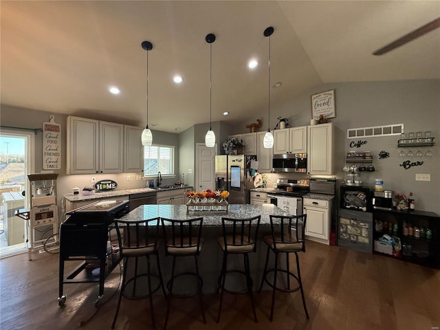 kitchen featuring appliances with stainless steel finishes, a center island, dark wood-type flooring, and a kitchen breakfast bar