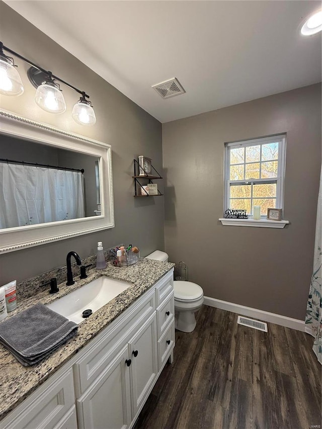 bathroom with baseboards, visible vents, wood finished floors, and vanity