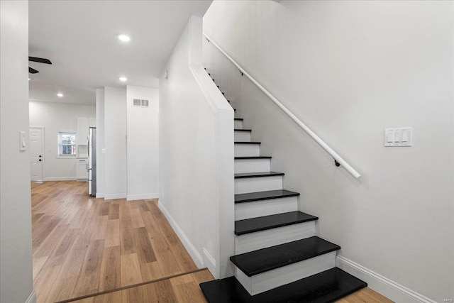 stairway featuring baseboards, visible vents, wood finished floors, and recessed lighting