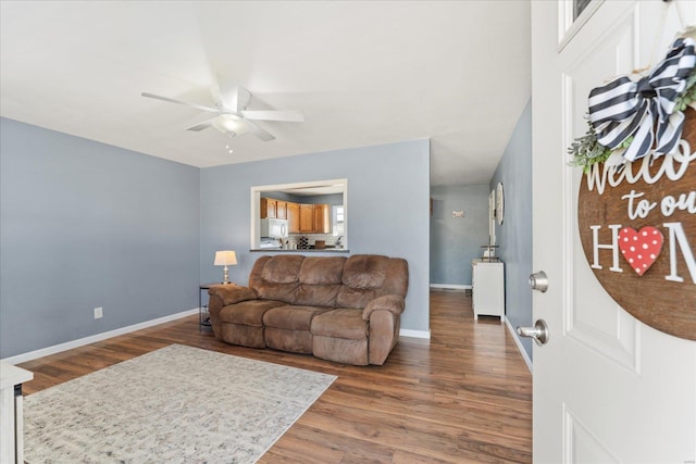 living room featuring ceiling fan, baseboards, and wood finished floors