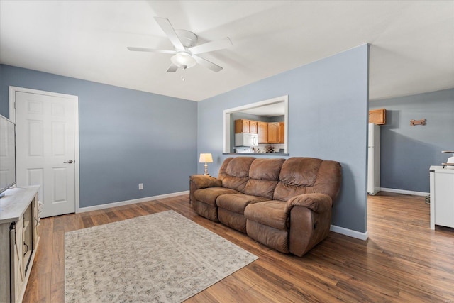 living area with a ceiling fan, baseboards, and wood finished floors