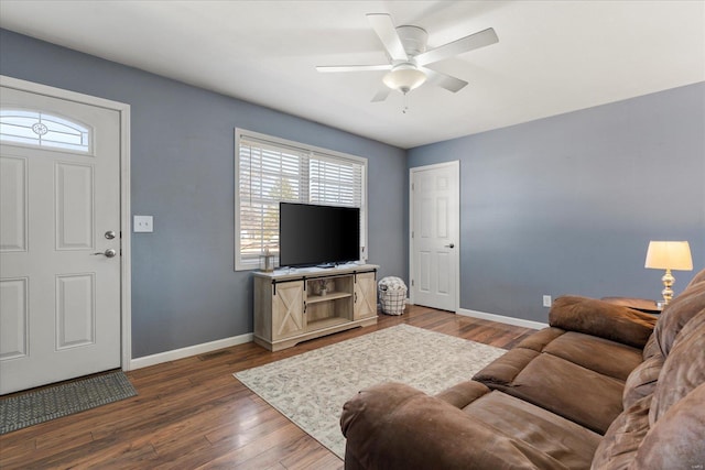 living area with dark wood-style flooring, a ceiling fan, and baseboards