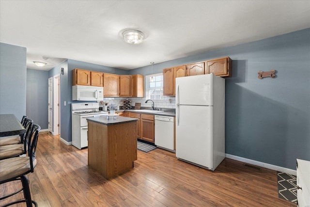 kitchen featuring white appliances, tasteful backsplash, baseboards, dark wood-style floors, and a kitchen island