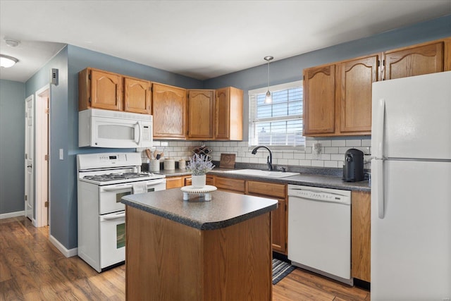 kitchen featuring tasteful backsplash, dark countertops, white appliances, and a sink