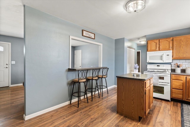 kitchen featuring tasteful backsplash, dark countertops, white appliances, and dark wood-style floors