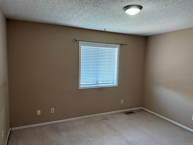 carpeted empty room with a textured ceiling, visible vents, and baseboards