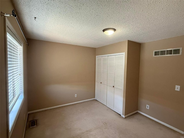 unfurnished bedroom featuring baseboards, visible vents, a closet, and carpet flooring