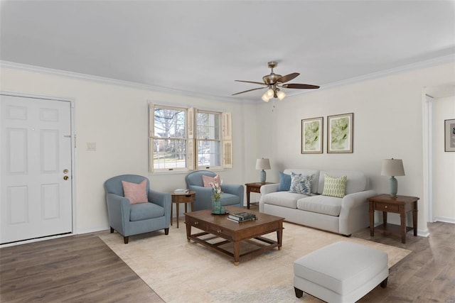 living area with crown molding, a ceiling fan, baseboards, and light wood finished floors