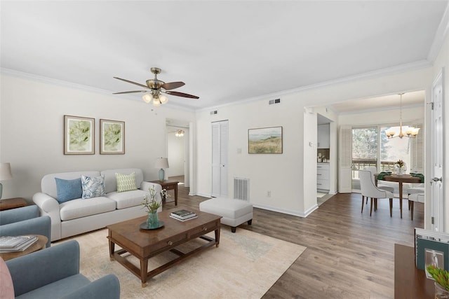 living area with light wood-style floors, visible vents, and ornamental molding