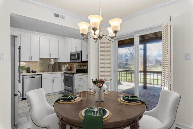 dining area featuring crown molding, a notable chandelier, and visible vents