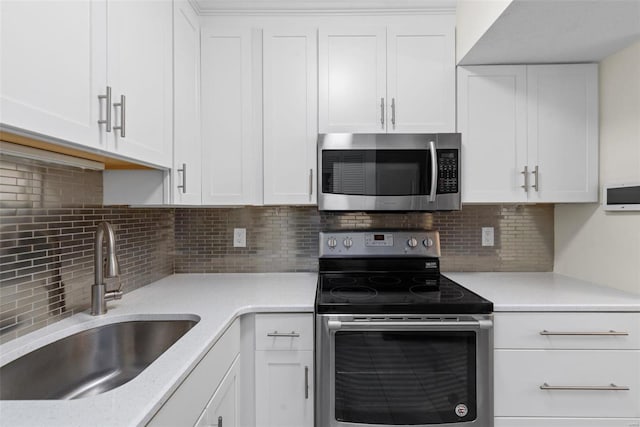 kitchen with a sink, stainless steel appliances, white cabinets, and light countertops