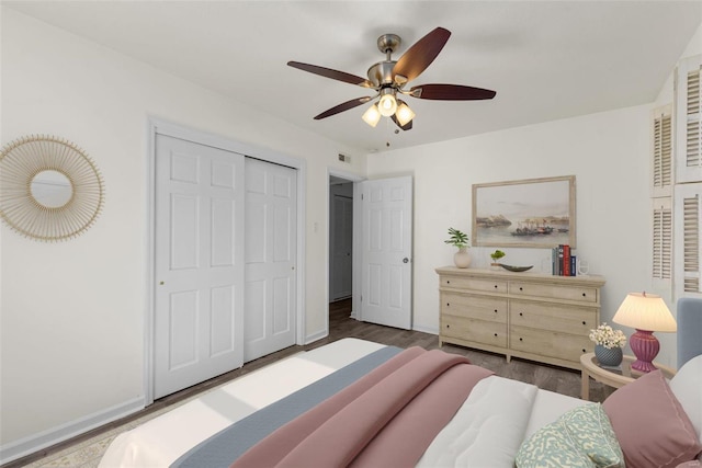 bedroom with a ceiling fan, wood finished floors, visible vents, baseboards, and a closet