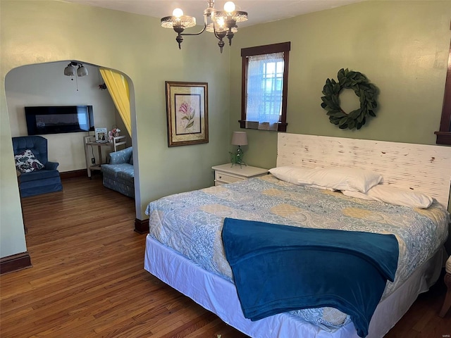 bedroom featuring a notable chandelier, arched walkways, wood finished floors, and baseboards