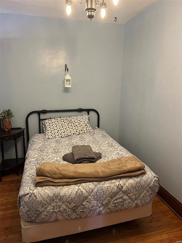 bedroom featuring dark wood-style floors, a chandelier, and baseboards