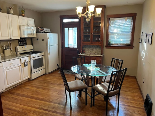 kitchen with a healthy amount of sunlight, white appliances, glass insert cabinets, and wood finished floors