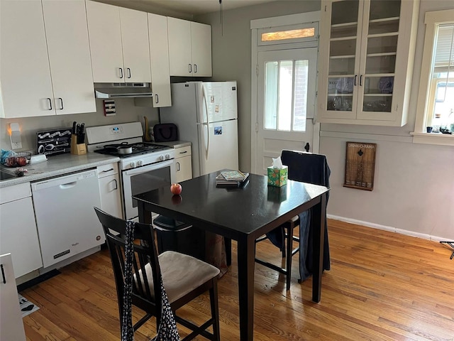 kitchen with light countertops, white cabinets, light wood-type flooring, white appliances, and under cabinet range hood