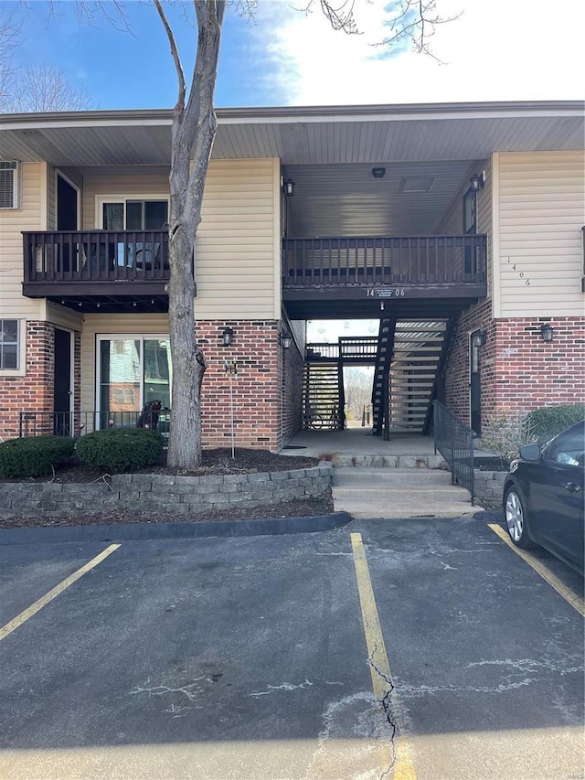 view of building exterior with uncovered parking and stairway