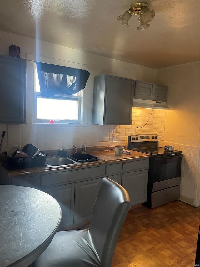 kitchen featuring backsplash, stainless steel range with electric cooktop, a sink, a textured ceiling, and under cabinet range hood