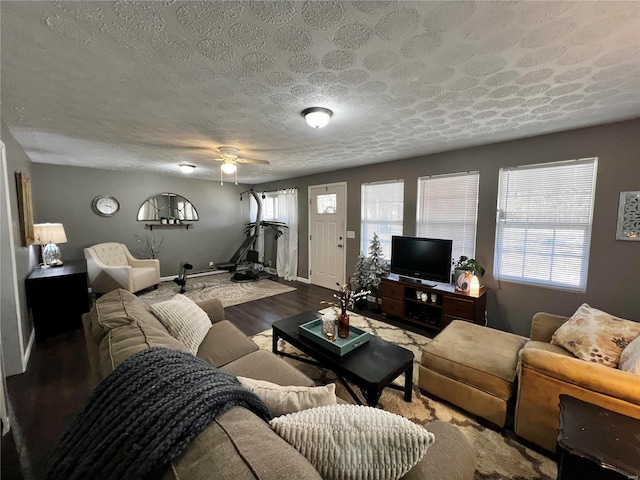 living room with ceiling fan, a textured ceiling, baseboards, and wood finished floors