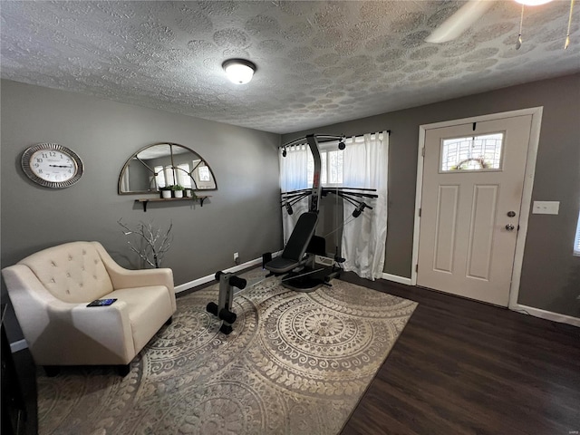 workout room with a textured ceiling, wood finished floors, and baseboards