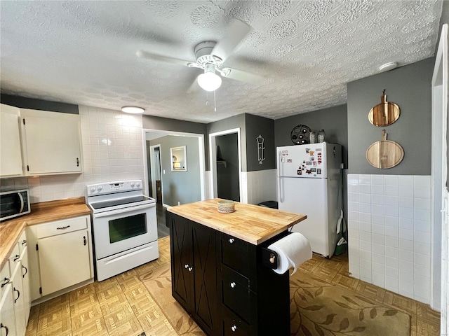 kitchen featuring white appliances, dark cabinets, wooden counters, and a textured ceiling