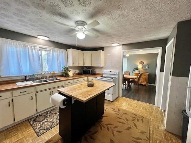 kitchen with a sink, wood counters, light floors, stainless steel microwave, and white electric range oven