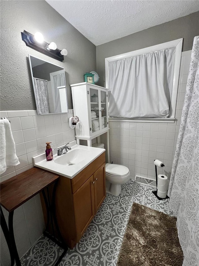 full bath featuring a textured ceiling, toilet, tile walls, and tile patterned floors