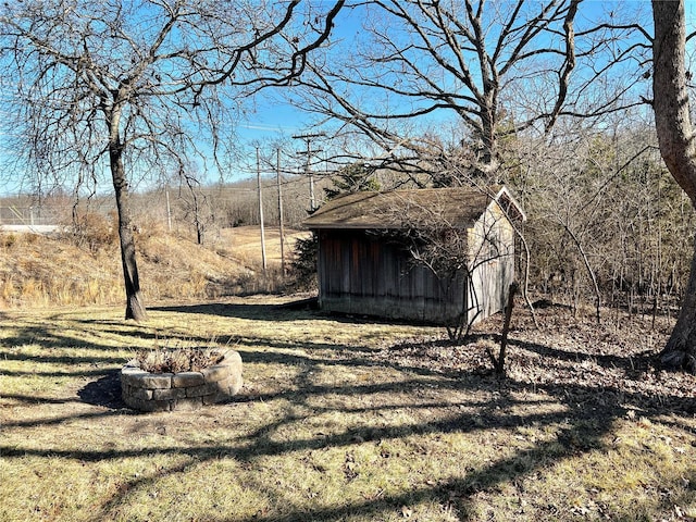 view of yard with an outbuilding, a shed, and a fire pit