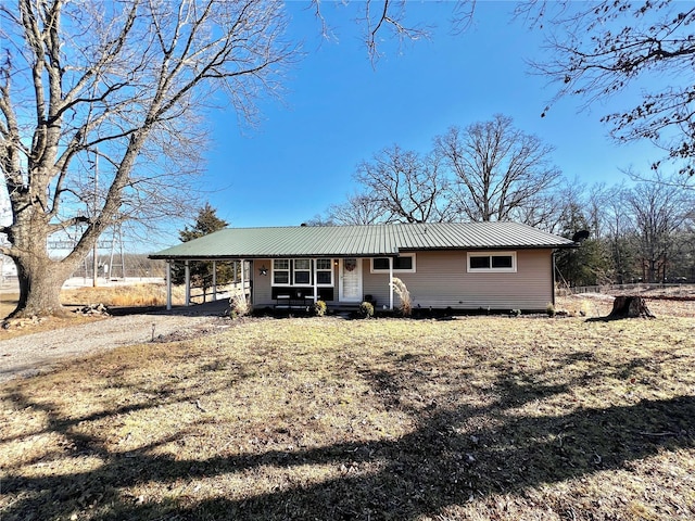 view of front of property with dirt driveway, metal roof, a carport, and a porch