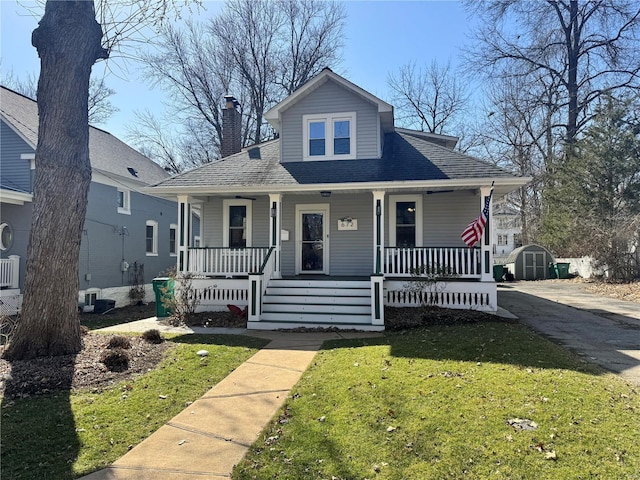 bungalow-style home featuring a front lawn, central AC, a porch, a storage shed, and an outdoor structure