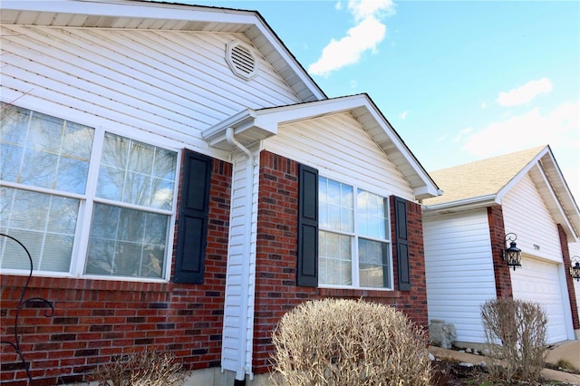 view of side of home featuring brick siding and an attached garage