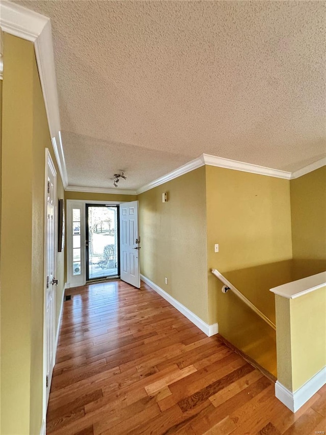 interior space with a textured ceiling, crown molding, and wood finished floors