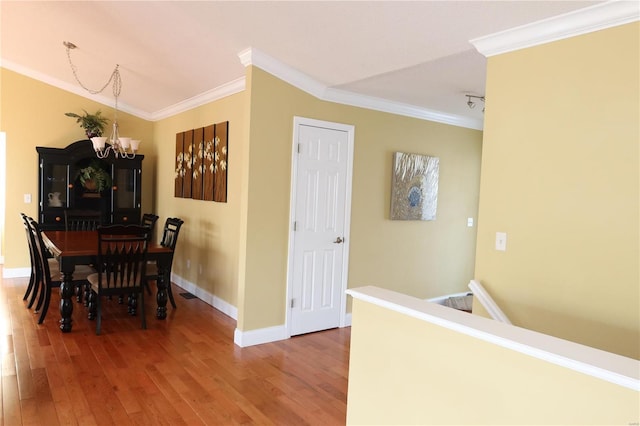 dining space with baseboards, an inviting chandelier, wood finished floors, and crown molding