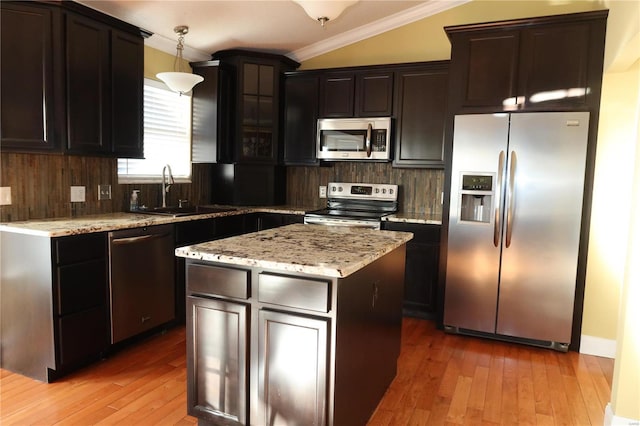 kitchen with light wood finished floors, ornamental molding, a sink, appliances with stainless steel finishes, and tasteful backsplash