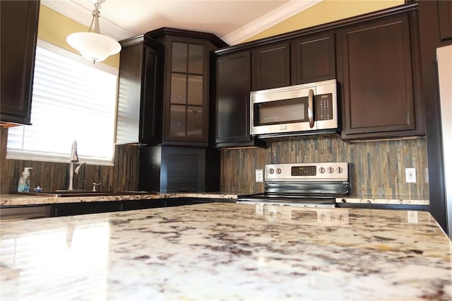 kitchen with dark brown cabinets, glass insert cabinets, crown molding, decorative backsplash, and appliances with stainless steel finishes