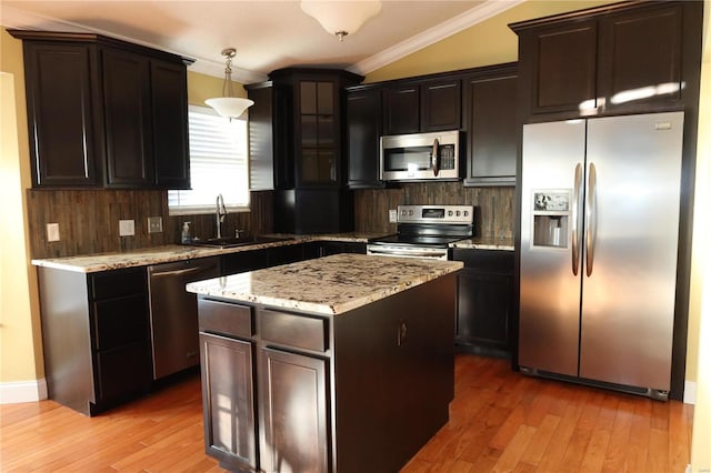 kitchen featuring light wood-type flooring, a sink, backsplash, appliances with stainless steel finishes, and crown molding