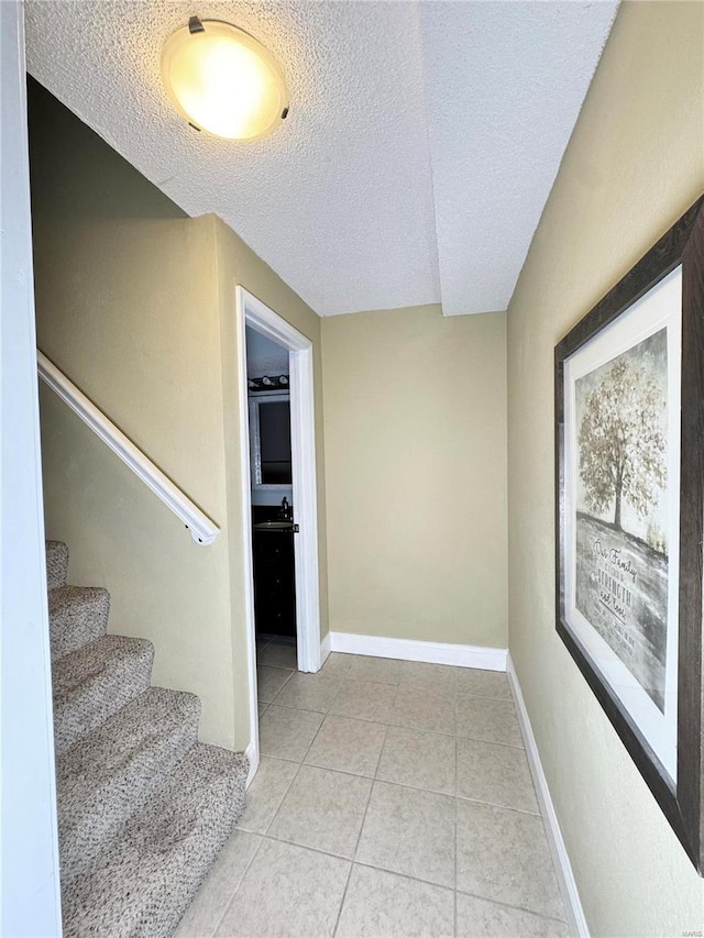 interior space featuring tile patterned floors, baseboards, and a textured ceiling