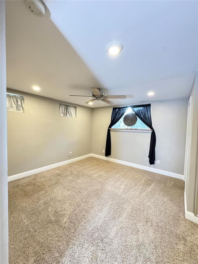 below grade area with carpet flooring, baseboards, a wealth of natural light, and ceiling fan