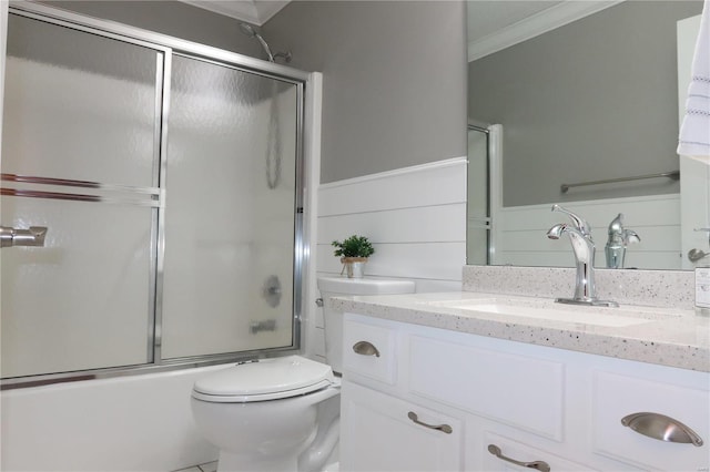 bathroom with shower / bath combination with glass door, ornamental molding, vanity, and toilet