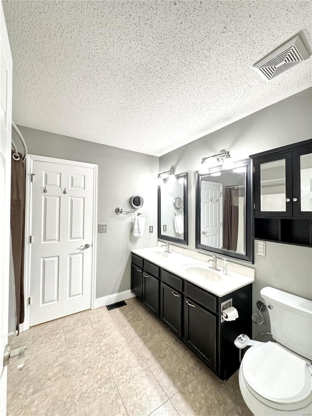 bathroom featuring a sink, visible vents, toilet, and double vanity