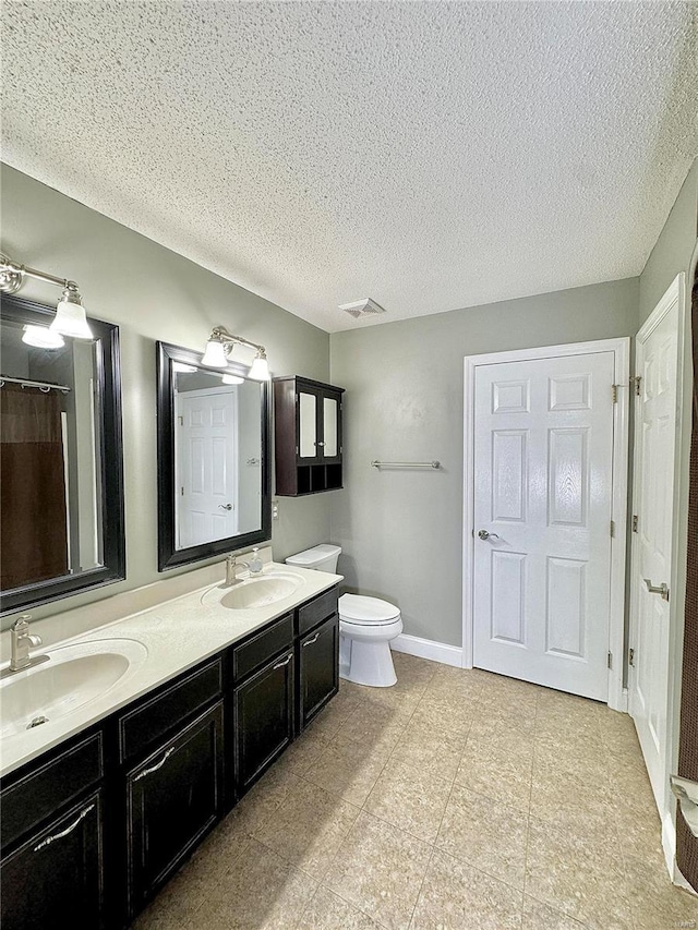 bathroom featuring a sink, visible vents, a textured ceiling, and double vanity