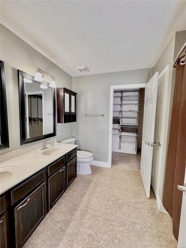 bathroom featuring a sink, visible vents, a textured ceiling, and double vanity